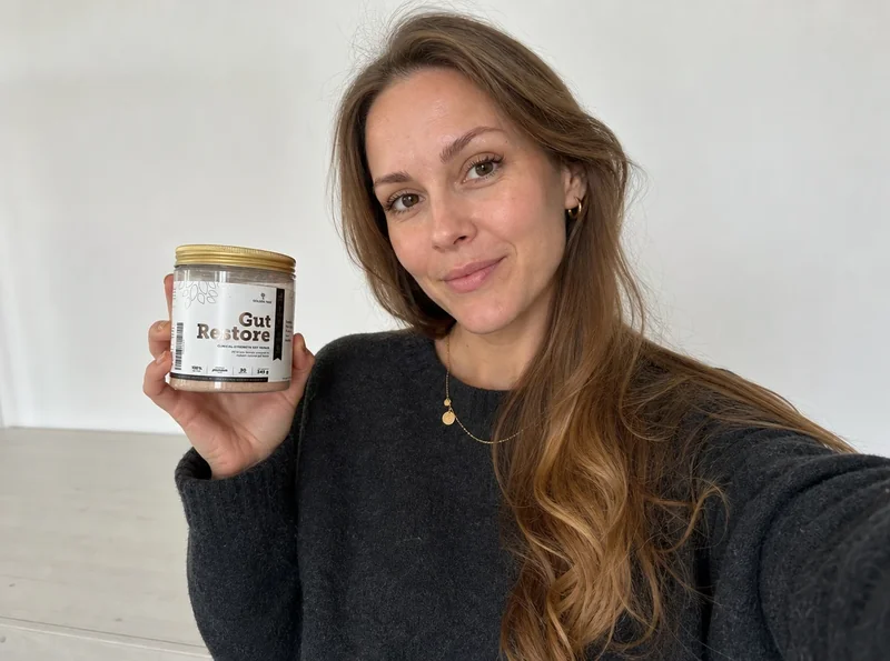Young woman holding gut supplement selfie